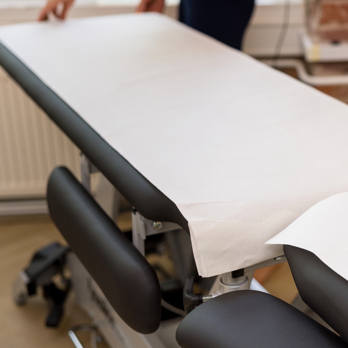 Valge massaažilaua kaitsepaber, mida kasutab massöör.